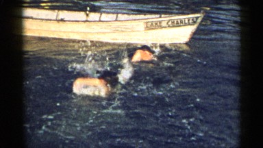 1954: Swimmers Swimming Towards Wooden Canoe Named Lake Charles New York