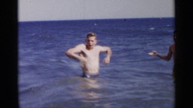 1954: a trio of male friends play in the surf and splash one another. NEW YORK