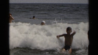 1954: kids and guys are taking bath at the ocean for their vacation holidays