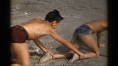 1954: a group of boys forms a human-caterpillar heading towards the ocean