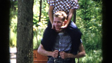 1954: a child is climbing on his brother's shoulder, happy NEW YORK