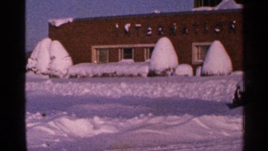 1965: snow covered brick, professional building and bushes after a blizzard