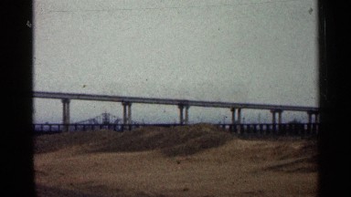 1960: long bridge extending towards a bridge with a dirt path by the train