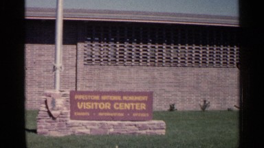 1960: a board that has the word visitor center and a small falls from a mountain