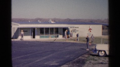 1960: a small group of people mill around in front of a business in the plains.