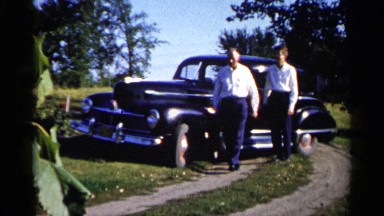 1961: Man Watches Nature View Near Blue Car and Big Tree