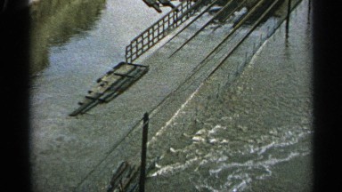 1965: bridge and building being flooded with water overtaking the street