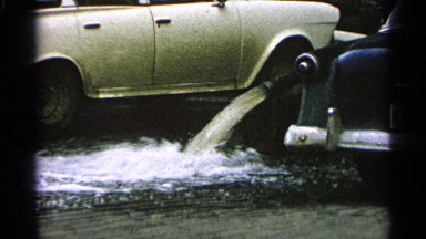 1965: dirty water flows from hose and building is partly submerged in flood