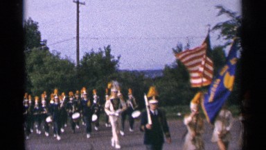 1964: group of marching band members parading through the street