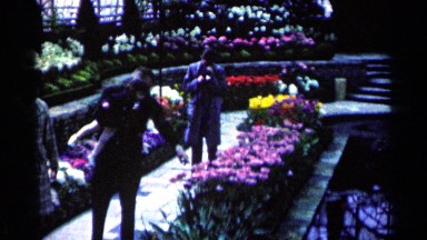 1964: man, woman, and child walking through a flower garden