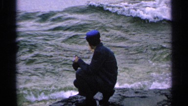 1964: man in blue hat watches the waves and takes a picture WASHINGTON ISLAND