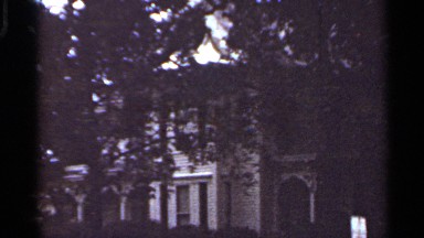 1965: a large building barely seen through the bushy trees branches. KANSAS CITY