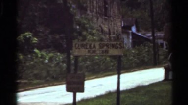 1965: a board that represent eureka springs and a building located at the right