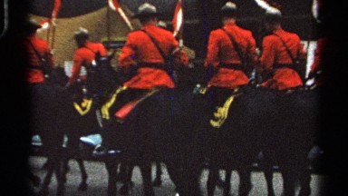 1965: a parade of scarlet-clad men ride jauntily, on horseback