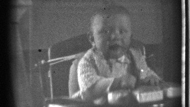1939: little baby child propped up on his or her chair laughing and playing