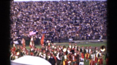 1944: large crowd of people at a sports event watching a marching band perform