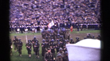 1944: people wearing military outfit parading in a stadium, and cheerleaders