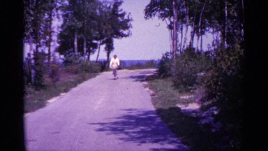 1960: a woman riding her bicycle down the street wearing a winter coat MICHIGAN