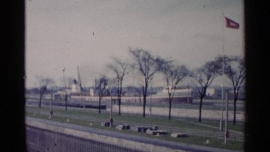 1960: a cruise liner is moving slowly as it is entering the port to have a halt