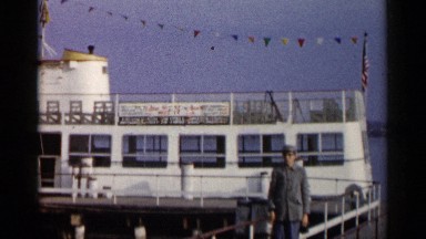 1960: beautiful boat around the middle of beach and person walks on bridge