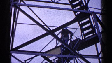 1960: a man holds tight to the handrails as he walks down a steep stairway