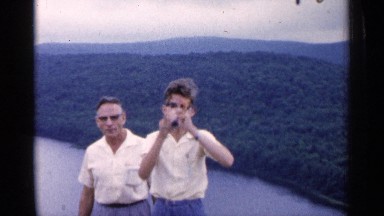 1960: two men watching the nature view and mountain and tree,green grasses river