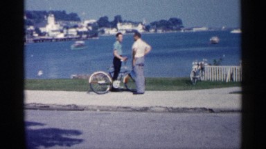 1960: two man watch the ocean come the ship long distance side the huge building