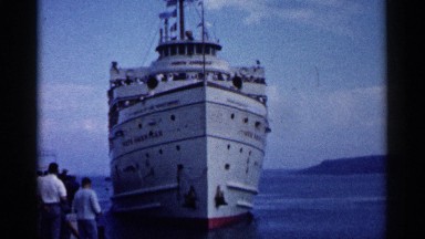 1960: a group of people on a pier watching a large ship approach the dock.
