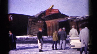 1961: group of men standing standing around looking at damaged freight cars.