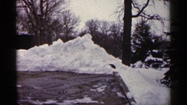 1961: road blocked by piled snowy ice cleared by person shoveling the snow.