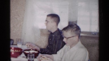 1961: couple of men having lunch at a table and one of them is coughing