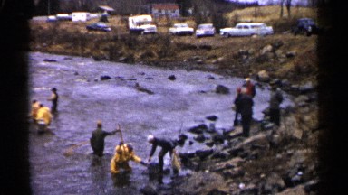 1961: people with yellow uniform and normal dressed people fishing in river