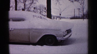 1961: a car located at the snow and some trees also near to the car