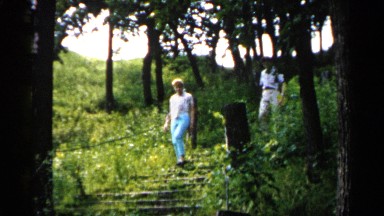 1961: man and woman descend an outdoor staircase, man swats at insects