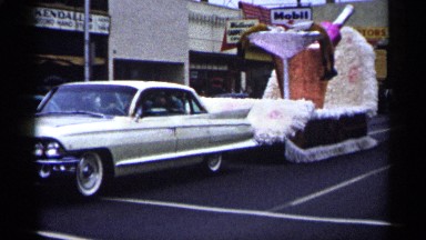 1961: a car pulls a float depicting a stem glass and mock alcoholic beverage