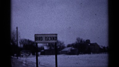 1961: a sign for bird island sits on a country road on a winter day MINNESOTA