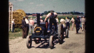 1963: farmer is riding a tractor on a sunny day at countryside, crops field