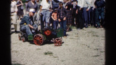 1963: man, in overalls, rides tiny tractor/train across uneven ground