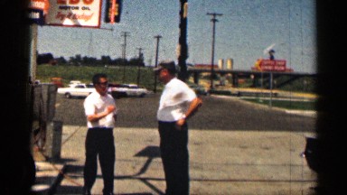 1963: two men wearing white shirts stand in the street, while another man cleans