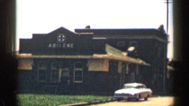 1963: a long road with big buildings as side painted in dark with parked car