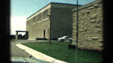 1963: a car slow drive in the residential area in the road near to another road