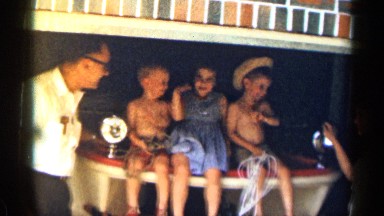 1963: three children seems to to sing a song sitting on a high table TEXAS