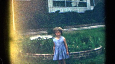 1963: two children playing in a front yard as a adult watches from the driveway.
