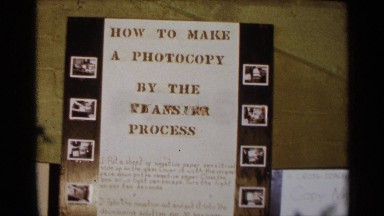 1963: A Board Displayed with Many Letters and Books at the Table
