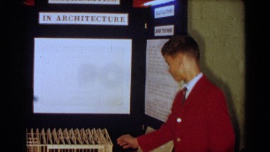 1963: with his booth set up a boy is showing off his popsicle stick house