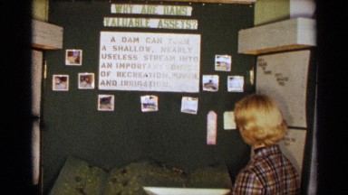1963: teenage girl wearing plaid jacket looks at school display about dam TEXAS