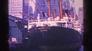 1964: ships waiting in the harbor to leave,surrounded by tall buildings.