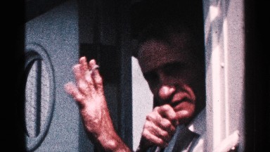 1964: a man watch flying in the air to flight near to lowest hills near to tree