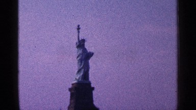 1964: draped statue of liberty holds torch high above the heads of visitors