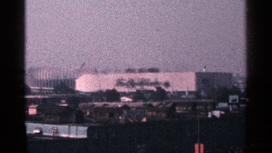 1964: long distance to view big building near tree stick and flag and road
